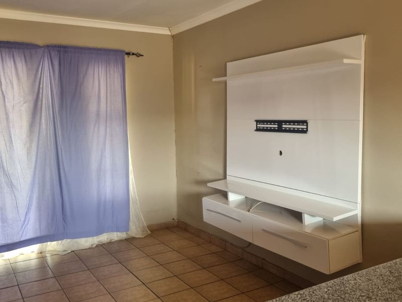 A living area featuring tiled flooring and a modern white built-in media unit, providing a clean and functional space for entertainment.