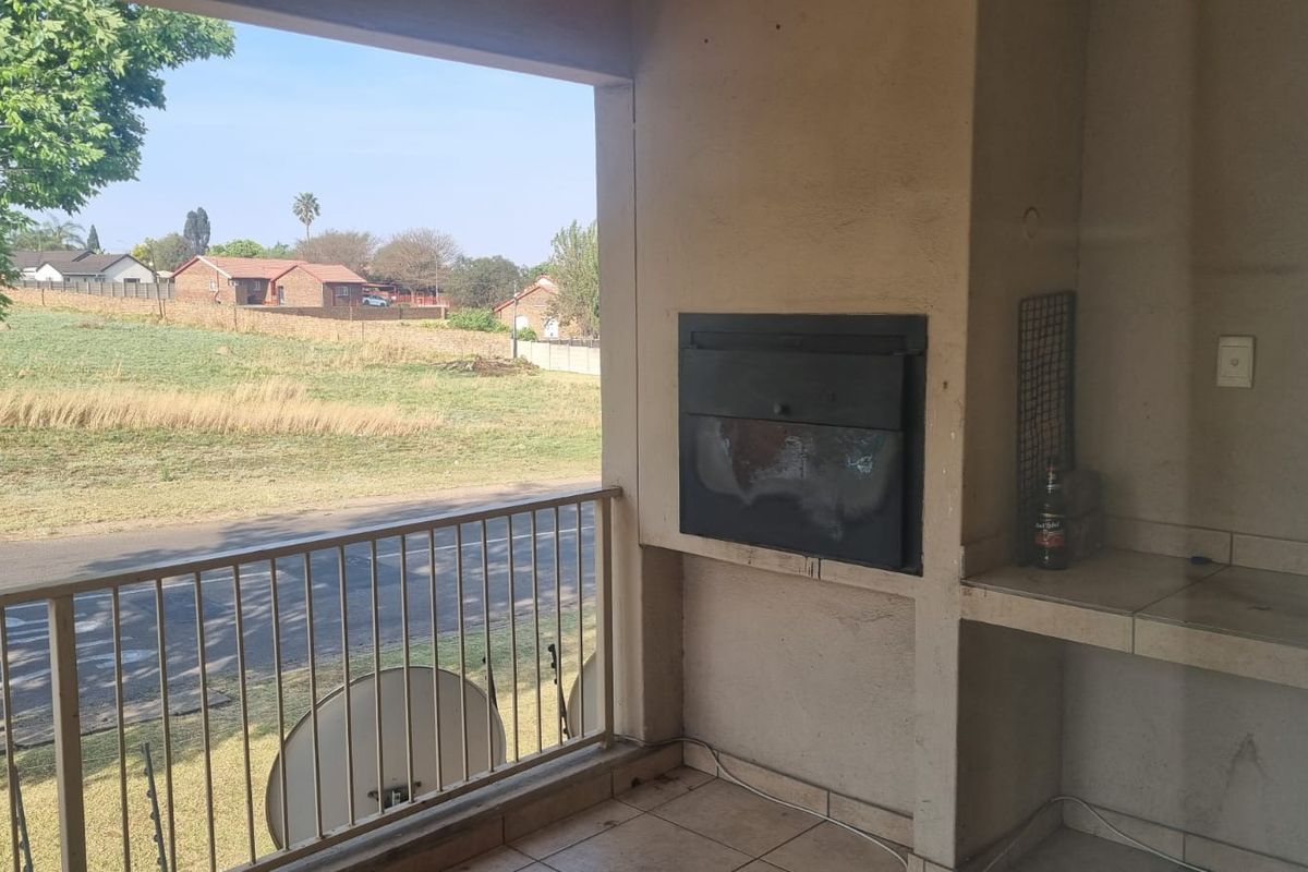 Covered balcony featuring a built-in braai, tiled flooring, and a metal balustrade, offering an open view of the surrounding neighbourhood.