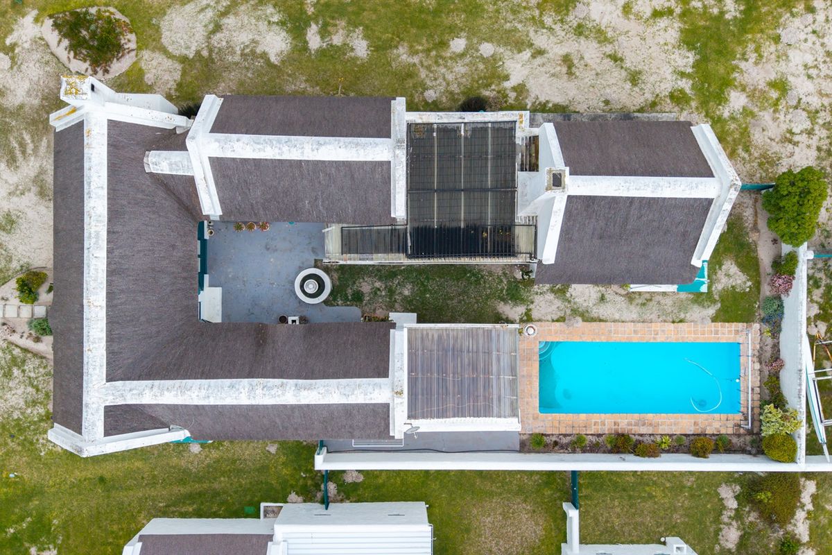 Aerial view of the property featuring a U-shaped layout with a thatched roof, central courtyard, and a private swimming pool.