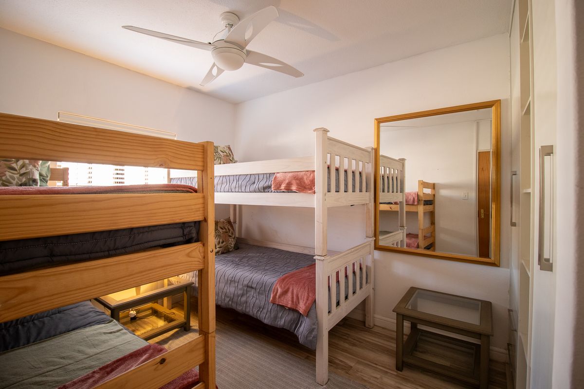 A functional bedroom featuring laminate flooring, a ceiling fan, and built-in wardrobe storage.