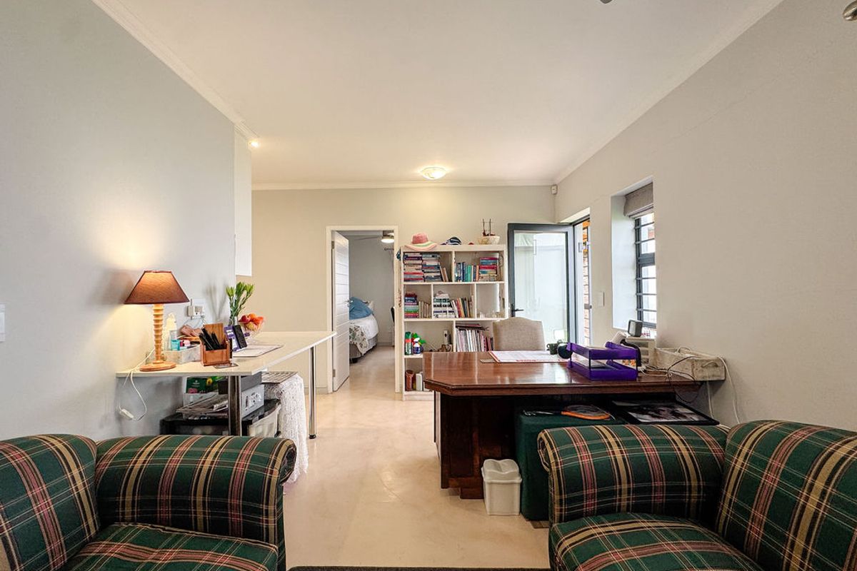 A functional living area featuring tiled flooring, recessed lighting, and a ceiling fan, with direct access to an adjacent bedroom and outdoor space.