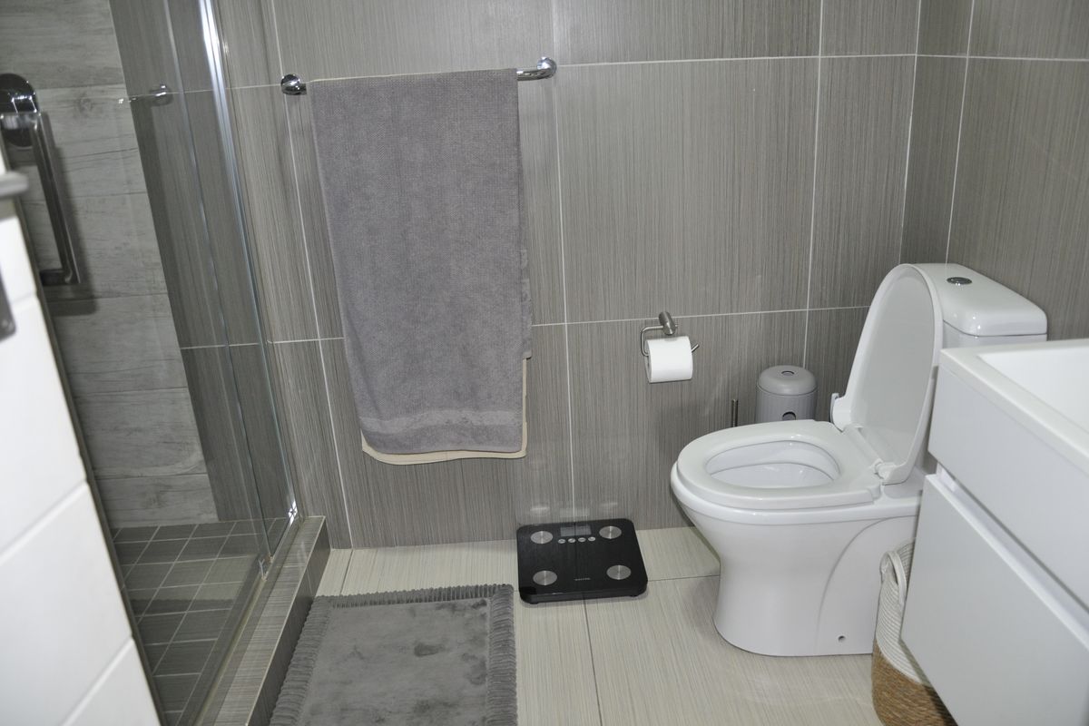 Modern bathroom featuring a glass-enclosed shower, wall-mounted toilet, and contemporary grey tiled finishes.