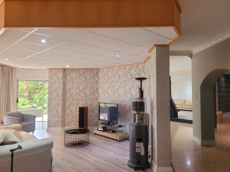 Spacious living area featuring a unique recessed ceiling, patterned wallpaper, and seamless transition to the outdoor patio through sliding glass doors.