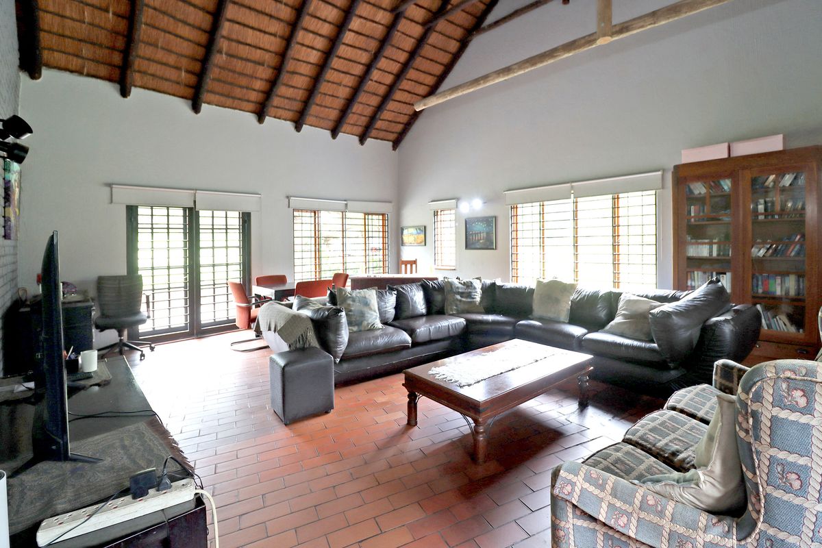 Spacious living room featuring a high vaulted thatched ceiling with exposed timber beams and traditional terracotta tile flooring, offering a rustic and airy atmosphere.