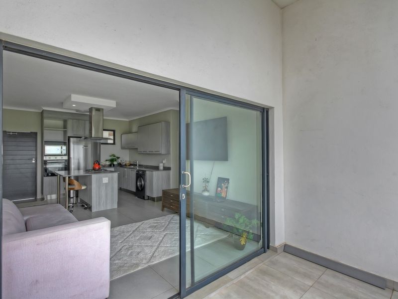 Modern open-plan living area featuring a contemporary kitchen with built-in cabinetry and seamless access to a private balcony through large sliding glass doors.