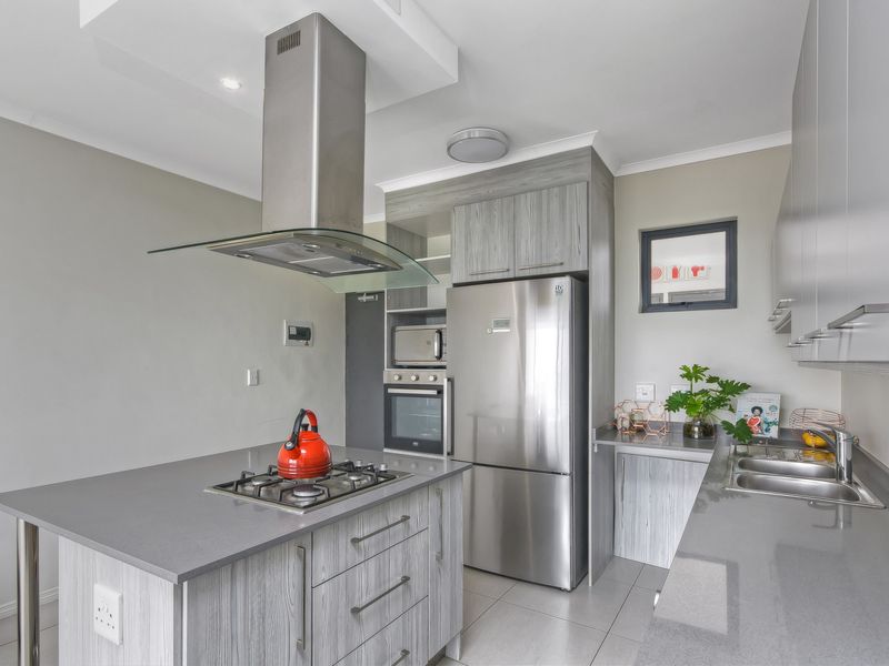 Modern kitchen featuring stone countertops, gas hob with extractor, built-in oven and microwave, and sleek laminate cabinetry.