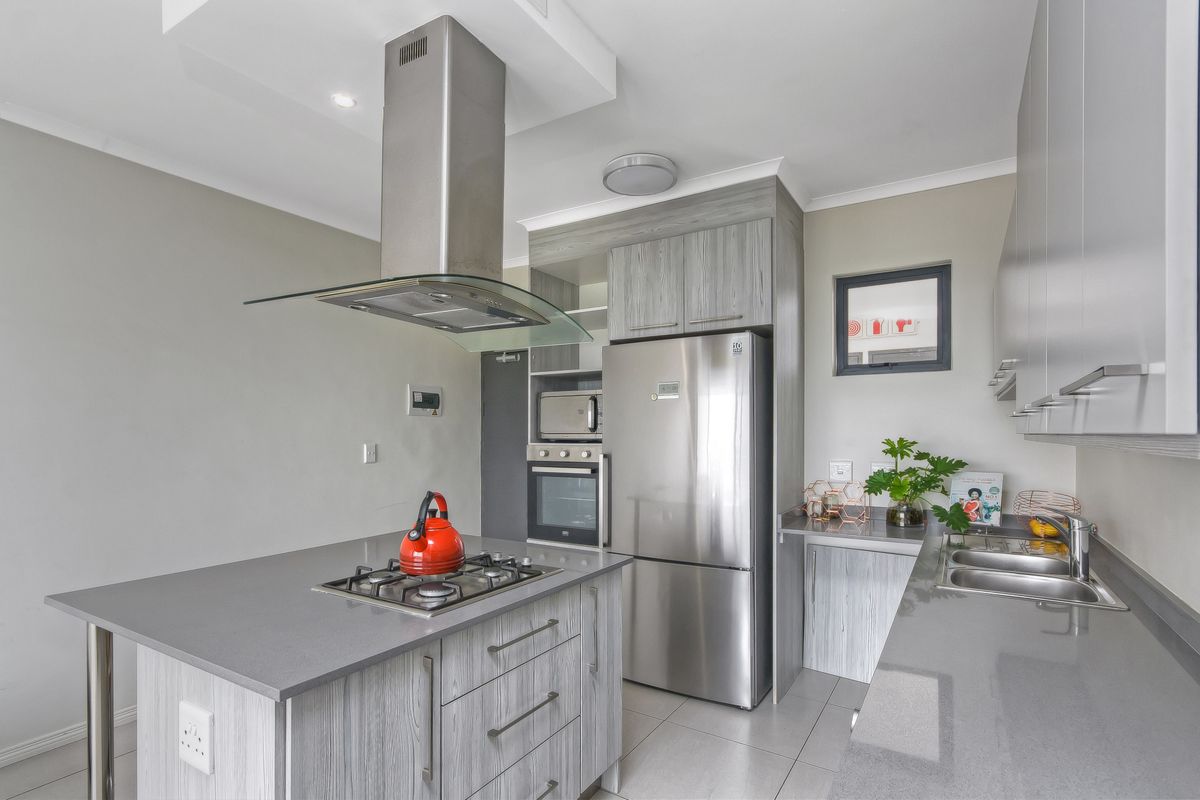 Modern kitchen featuring stone countertops, gas hob with extractor, built-in oven and microwave, and sleek laminate cabinetry.