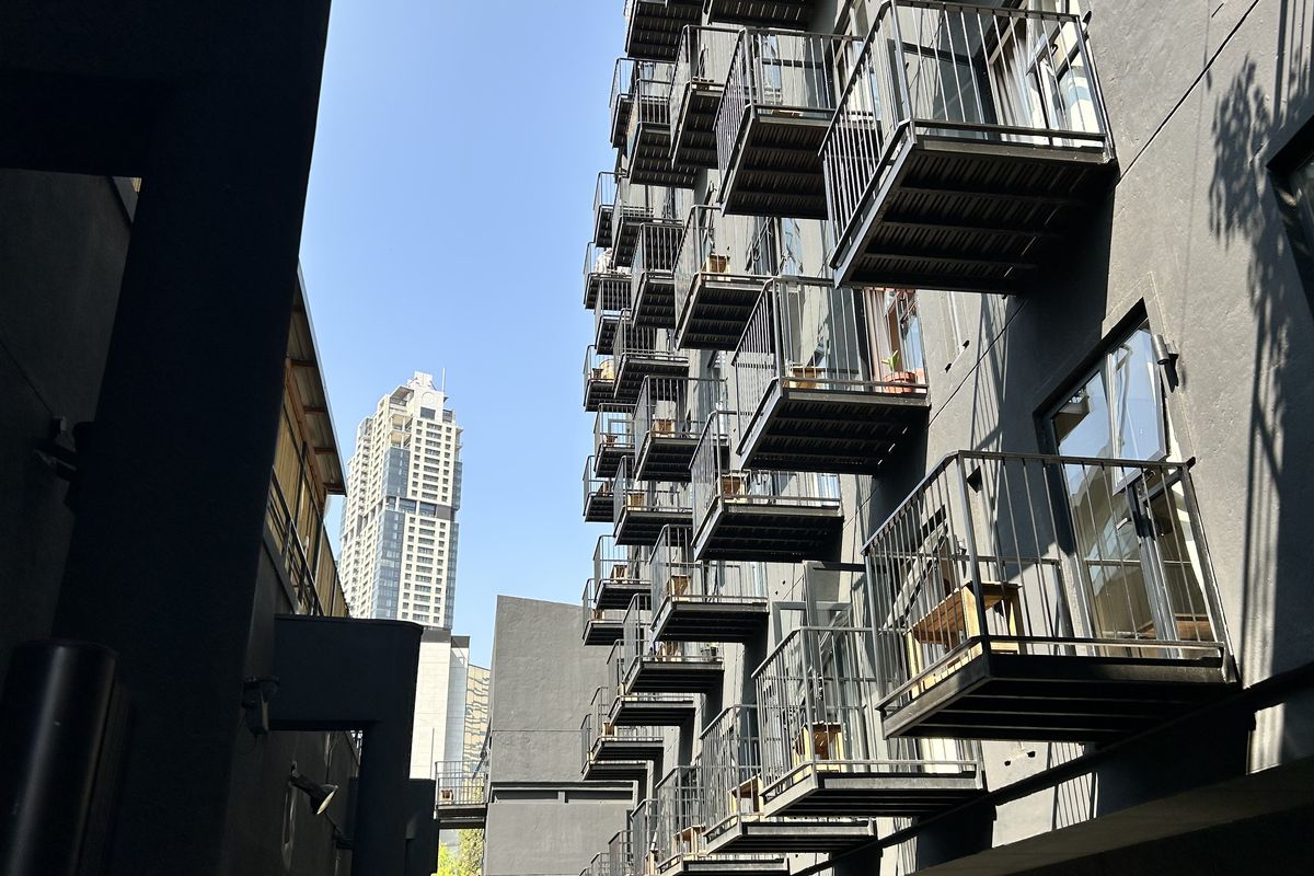 A view of the apartment building exterior featuring a series of stacked metal balconies and modern dark facade finishes.