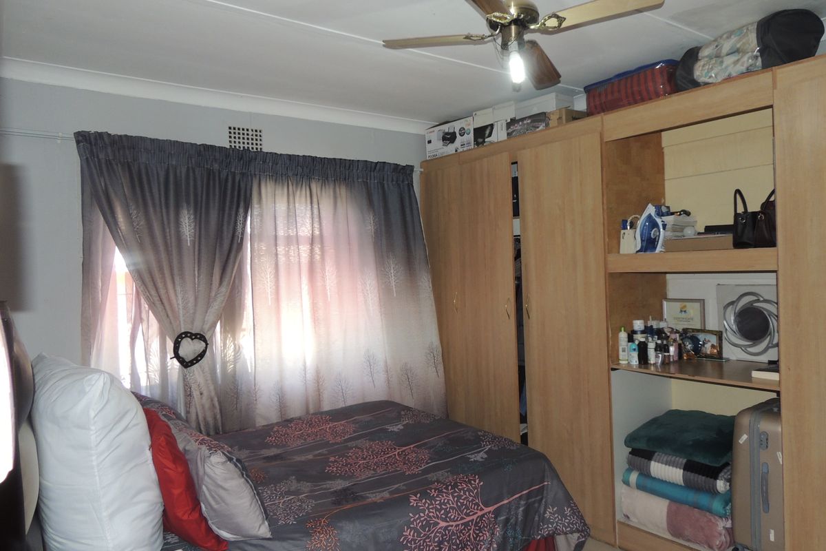 A bedroom featuring built-in wooden cupboards and a ceiling fan, providing functional storage and climate control.