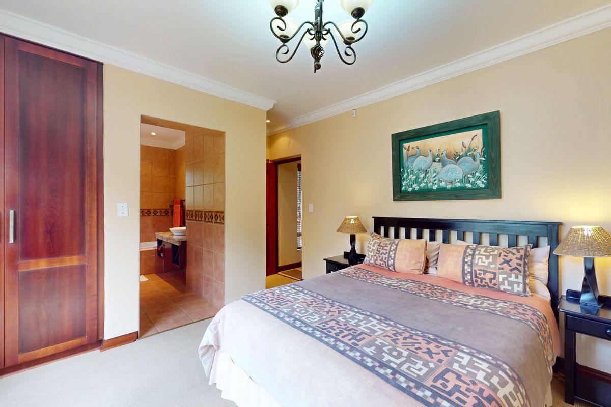 A well-maintained bedroom featuring built-in wooden wardrobes, neutral wall finishes, and direct access to an en-suite bathroom.