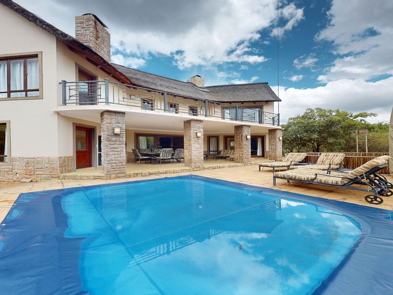 Spacious rear exterior featuring a swimming pool with cover, stone-clad pillars, and a large covered patio area with balcony access above.