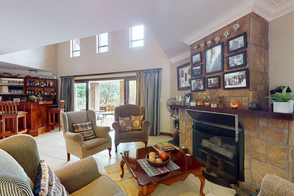 Spacious living room featuring a stone-clad fireplace, built-in bar area, and large sliding doors leading to an outdoor patio.