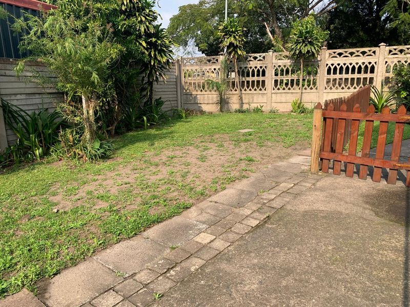 A private rear garden featuring a paved patio area, timber fencing, and a precast concrete boundary wall.