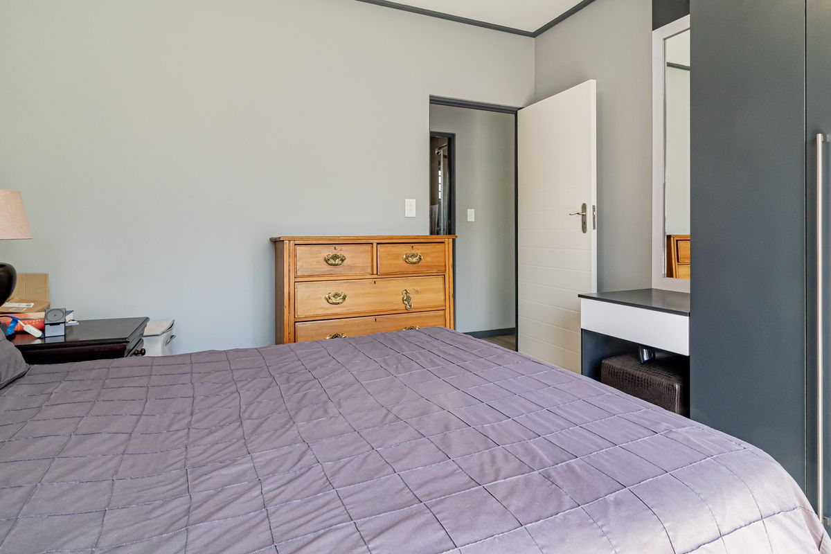 A well-maintained bedroom featuring a built-in wardrobe, integrated vanity, and an exposed concrete feature wall.
