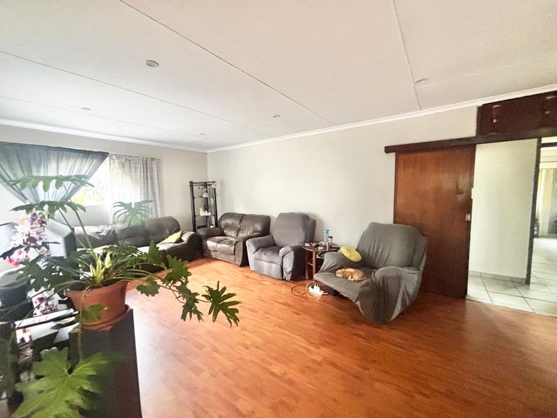 Spacious living room featuring laminate flooring, recessed downlighting, and a sliding wooden door leading to an adjacent area.