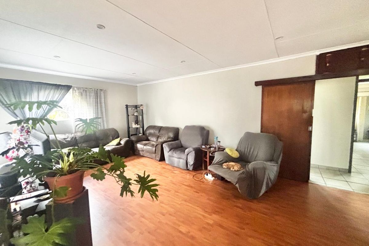 Spacious living room featuring laminate flooring, recessed downlighting, and a sliding wooden door leading to an adjacent area.