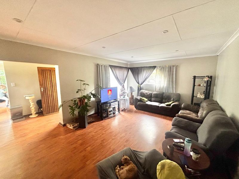 A spacious living room featuring laminate flooring, recessed downlighting, and a coved ceiling, providing a comfortable and functional family living area.