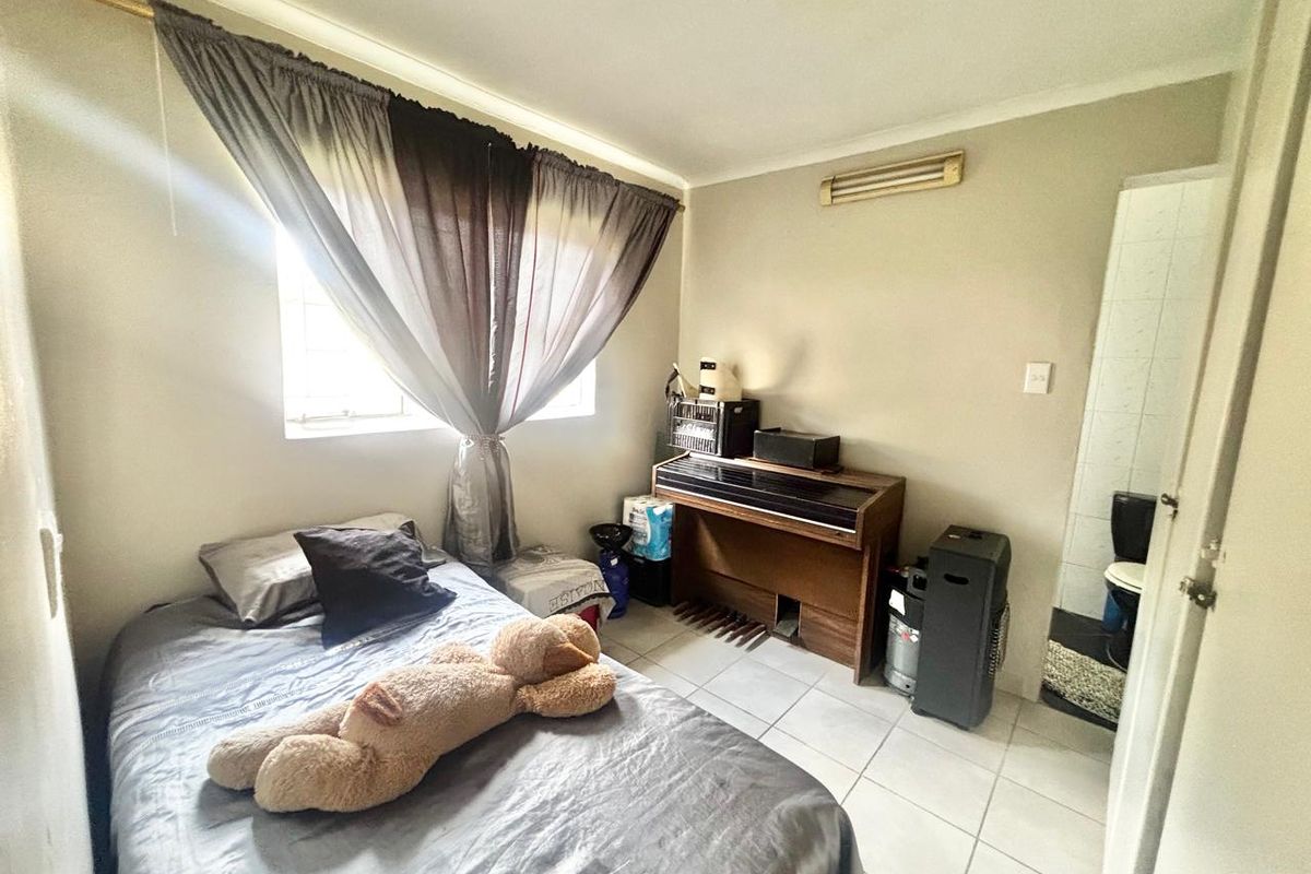 A functional bedroom featuring tiled flooring and an attached en-suite bathroom, providing a practical layout for comfortable living.