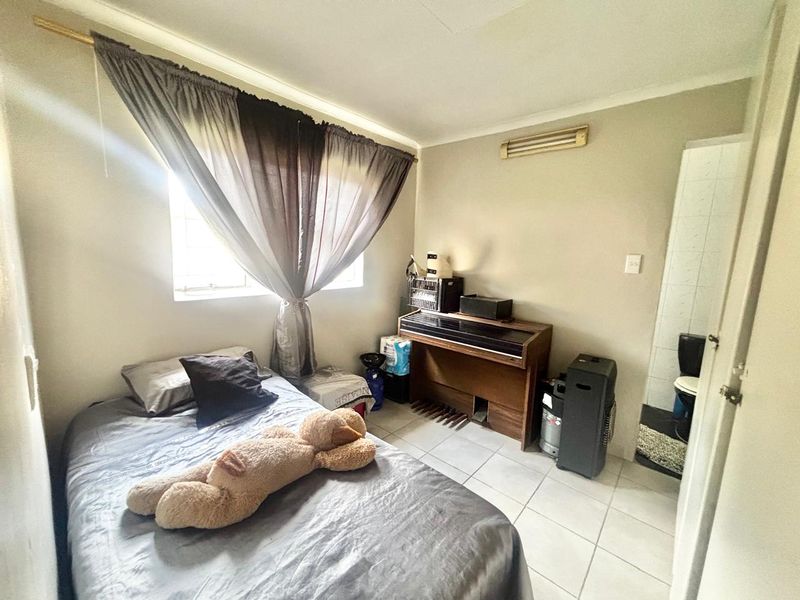 A functional bedroom featuring tiled flooring and an attached en-suite bathroom, providing a practical layout for comfortable living.