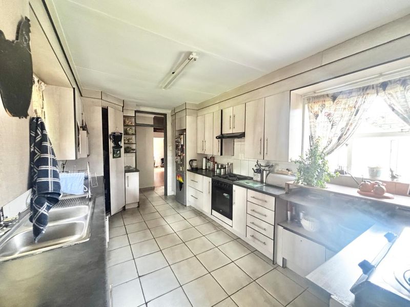 A functional kitchen featuring built-in cabinetry, a double basin sink, and integrated cooking appliances with tiled flooring throughout.