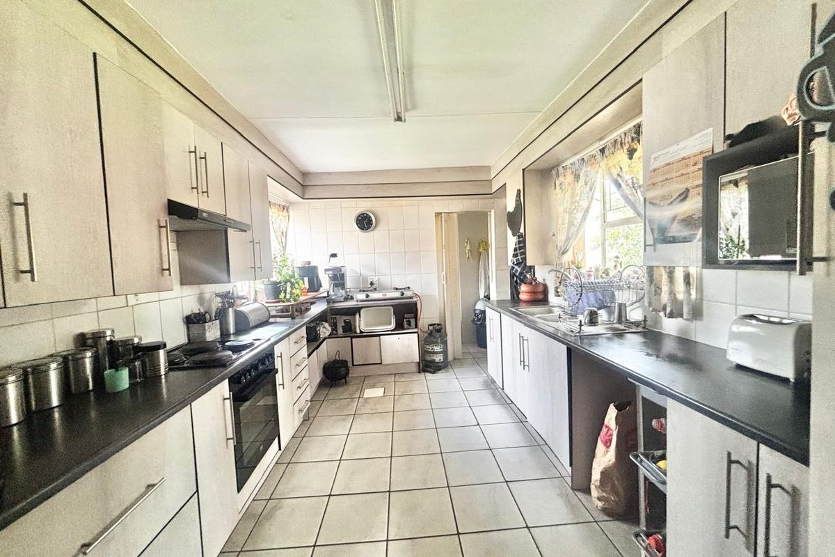 A functional galley-style kitchen featuring built-in cabinetry, tiled flooring, and a tiled splashback, offering a practical layout with potential for modern updates.