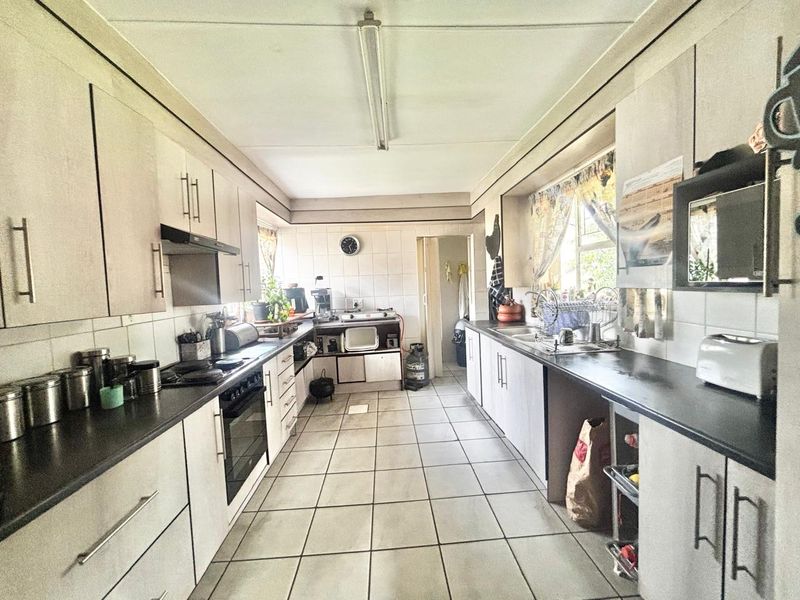 A functional galley-style kitchen featuring built-in cabinetry, tiled flooring, and a tiled splashback, offering a practical layout with potential for modern updates.