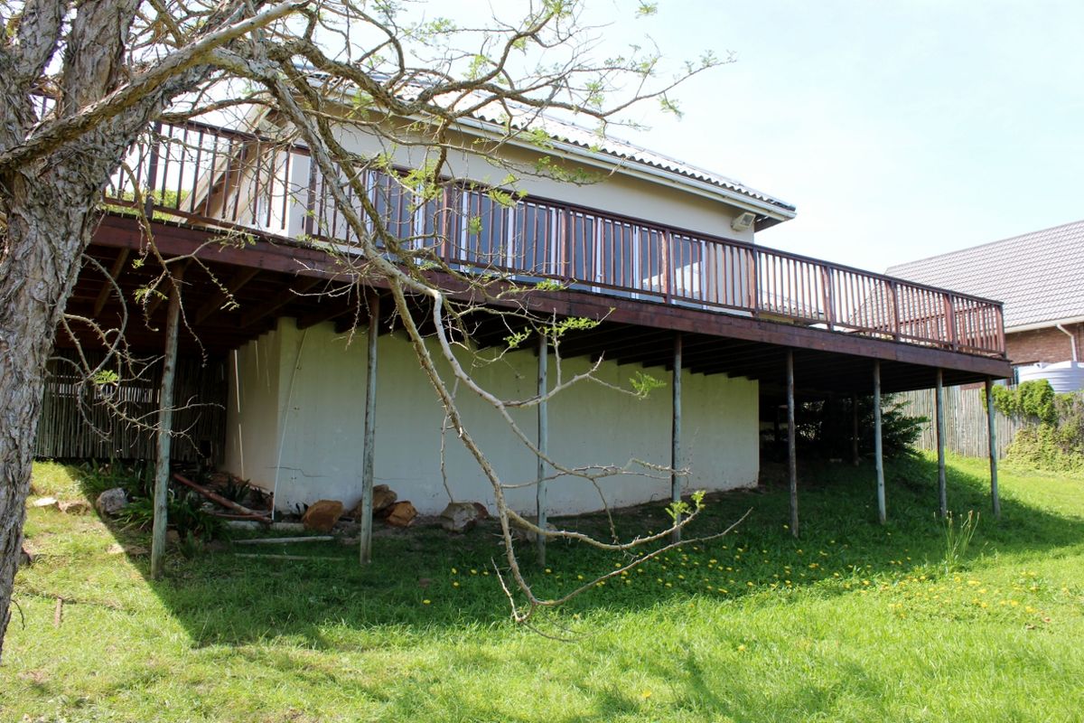 A rear view of the house featuring a large raised timber deck supported by steel posts, overlooking the backyard garden area.