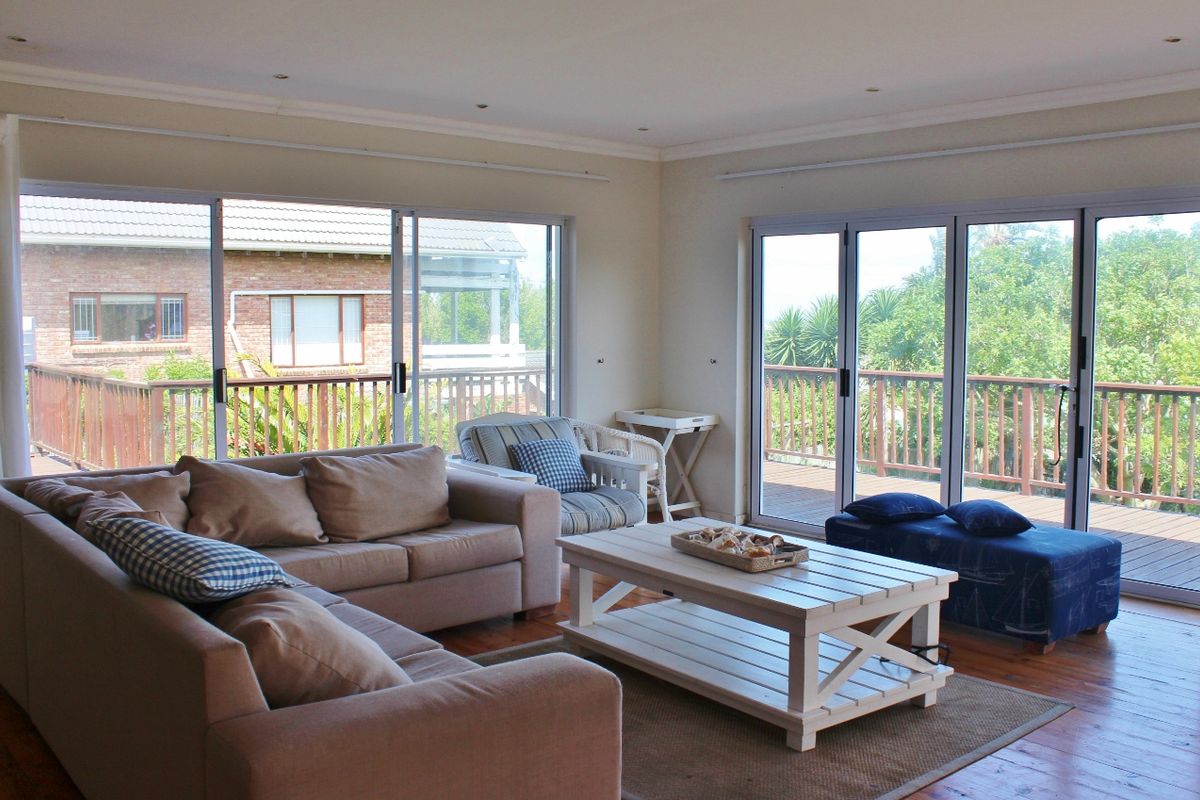 Spacious living room featuring wooden flooring, recessed lighting, and large sliding glass doors that open onto an elevated timber deck.