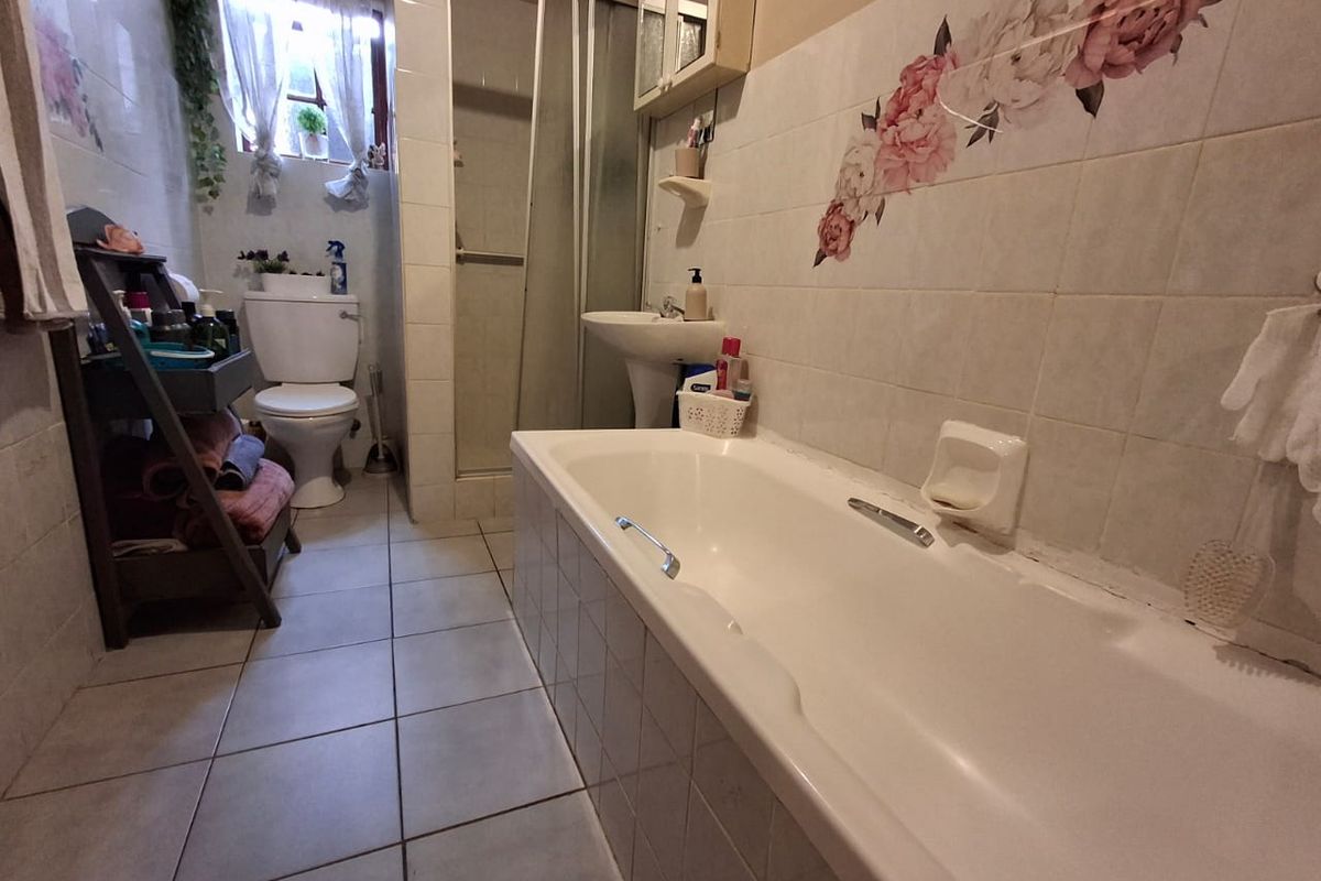 A functional bathroom featuring a bathtub, separate shower enclosure, pedestal basin, and toilet with tiled walls and flooring.