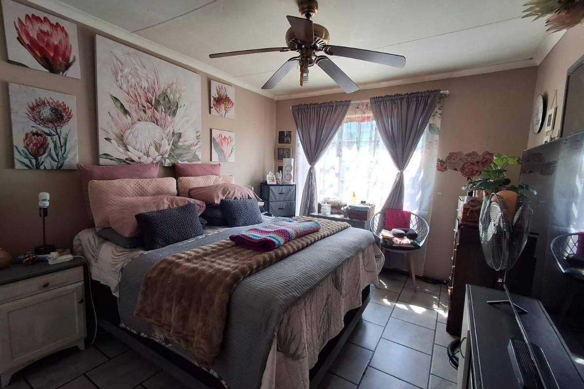 A bedroom featuring tiled flooring and a ceiling fan, offering a functional space with natural light from the window.