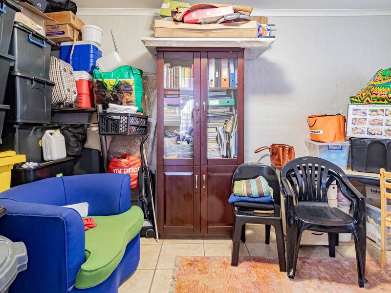 A utility or storage space featuring tiled flooring and coving, currently utilized for general storage.