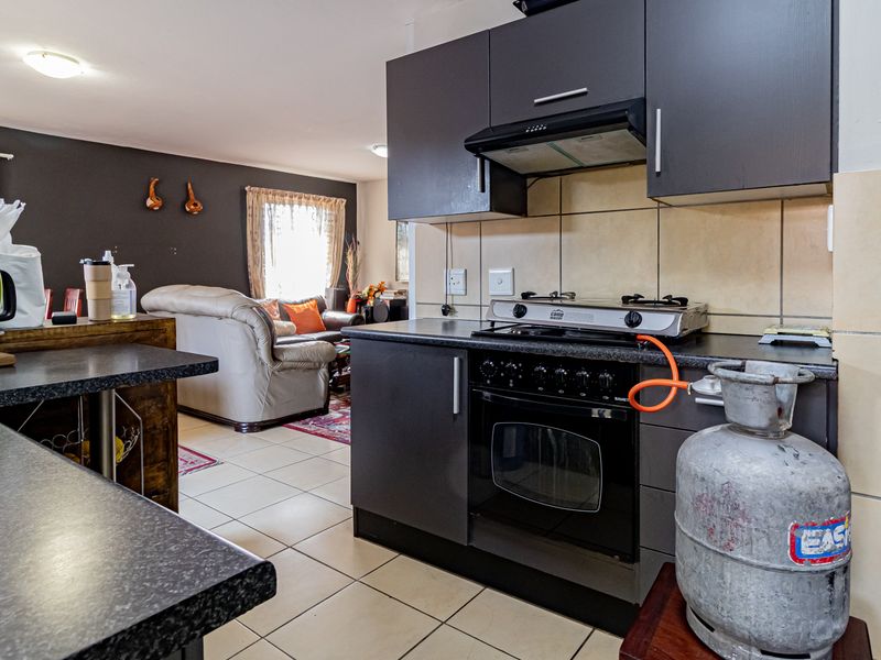 Open plan kitchen and living area featuring dark cabinetry, gas cooking appliances, and tiled flooring throughout.