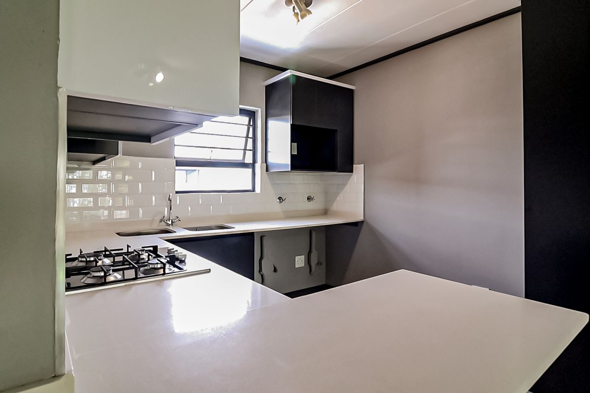 Modern kitchen featuring sleek cabinetry, stone countertops, a gas hob, and a clean subway tile backsplash in a bright, functional layout.