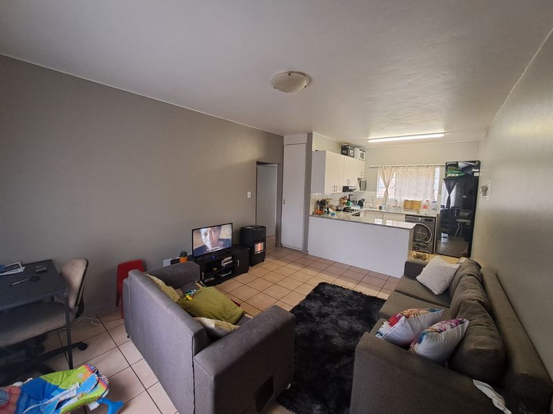 Open-plan living area featuring tiled flooring and a functional kitchen with built-in cabinetry and countertops, creating a combined living and dining space.