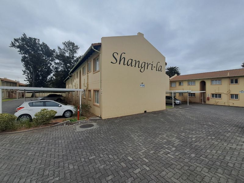 Exterior view of the Shangri-la apartment complex featuring paved parking areas and covered carports.