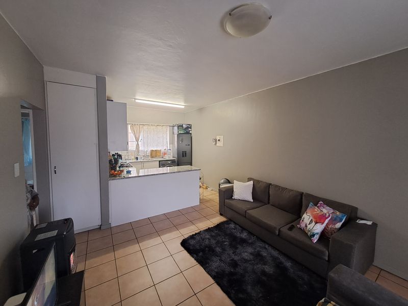 Open-plan living area featuring tiled flooring and a functional kitchen with built-in cabinetry and countertop space.
