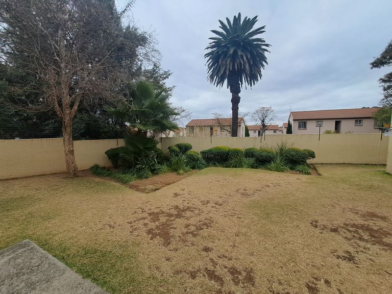 A private garden area featuring a perimeter wall with electric fencing and established landscaping.