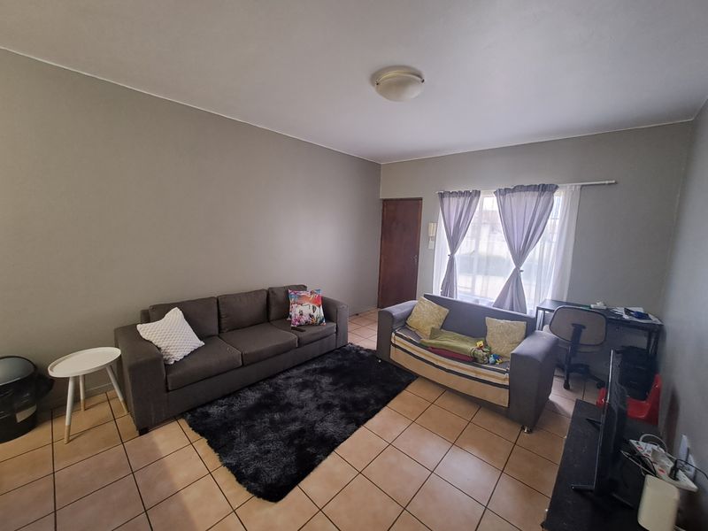 A functional living room featuring neutral wall paint, ceramic floor tiles, and an intercom system, providing a comfortable and practical living space.