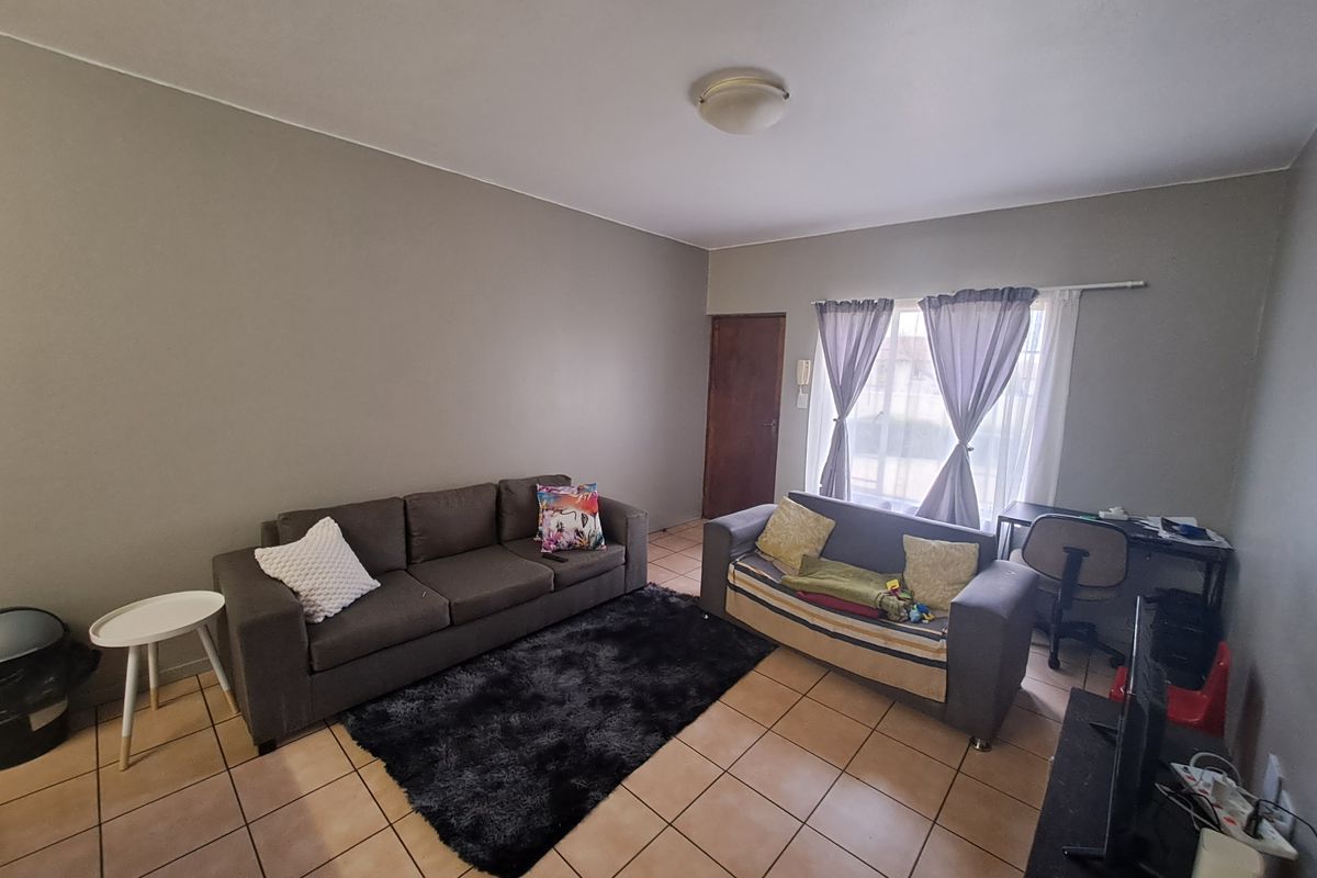 A functional living room featuring neutral wall paint, ceramic floor tiles, and an intercom system, providing a comfortable and practical living space.