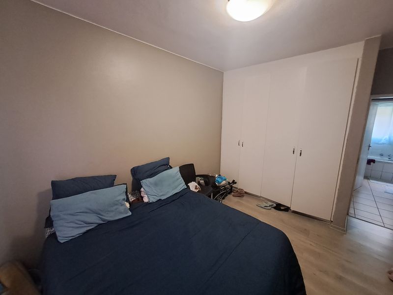 A bedroom featuring laminate flooring and built-in cupboards, with direct access to an adjoining bathroom.
