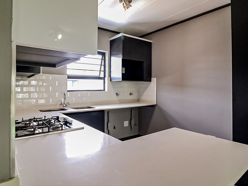 Modern kitchen featuring sleek cabinetry, stone countertops, a gas hob, and a clean subway tile backsplash in a bright, functional layout.
