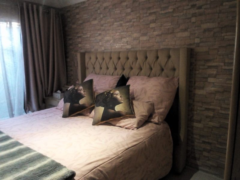 A bedroom featuring a textured brick-effect accent wall and a large upholstered headboard, creating a cozy and defined sleeping space.