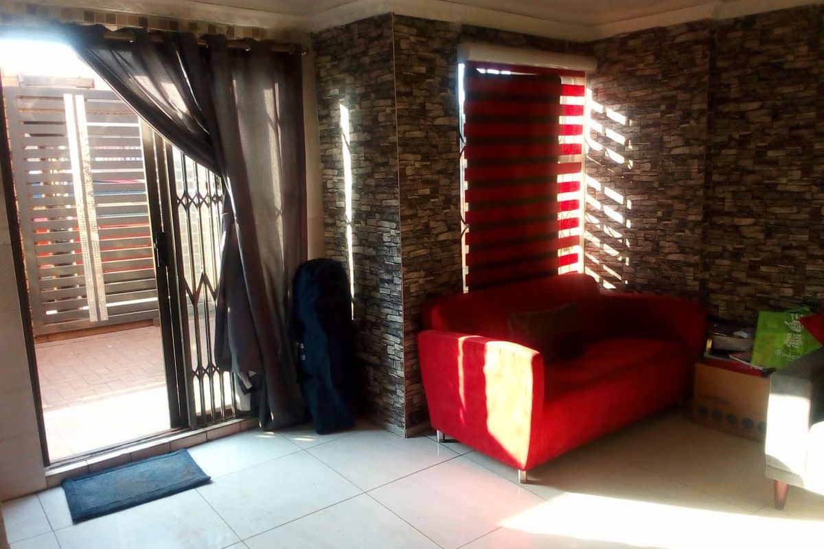 Living room featuring tiled flooring, stone veneer accent walls, and a sliding glass door providing access to an outdoor area.