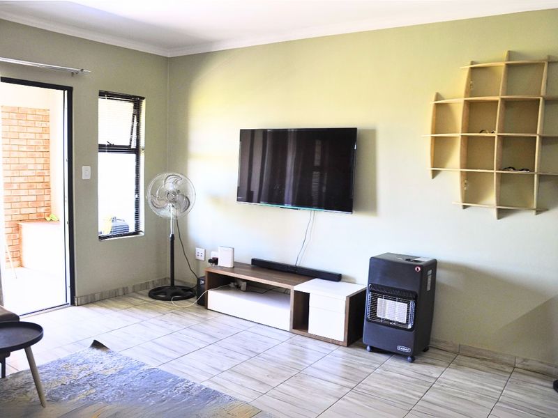 A living room featuring tiled flooring, neutral wall paint, and direct access to an outdoor patio area through a sliding door.