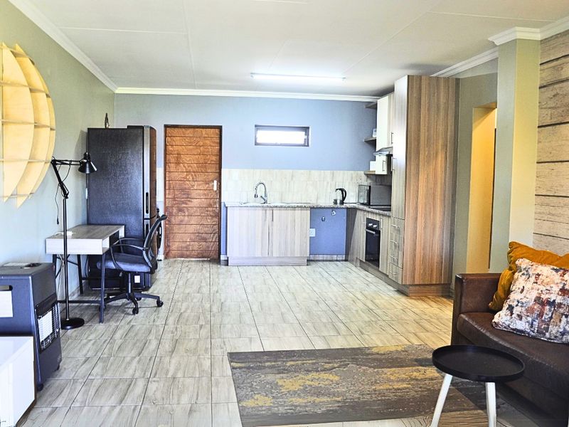 Open-plan living area featuring a functional kitchen with built-in cabinetry, granite countertops, and tiled flooring throughout.