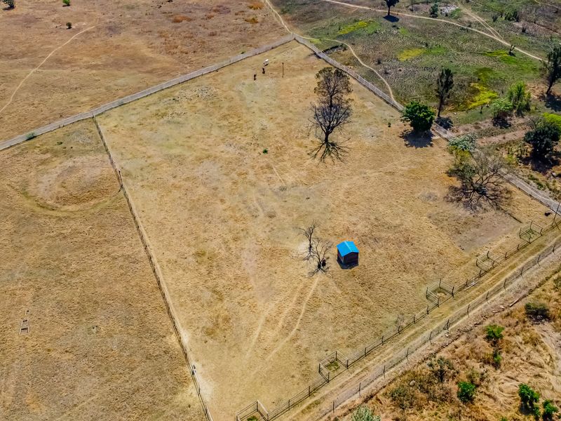 Aerial view of a large, vacant residential plot featuring perimeter fencing and a small detached shed on the property.