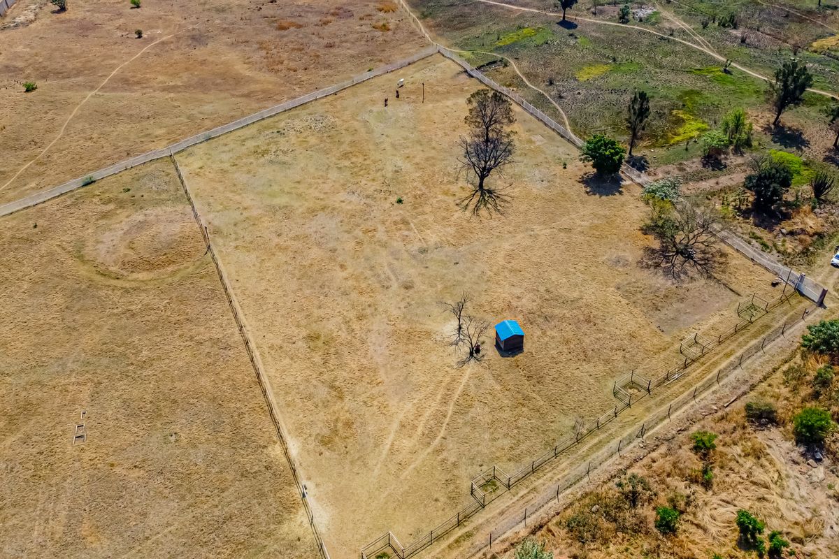 Aerial view of a large, vacant residential plot featuring perimeter fencing and a small detached shed on the property.