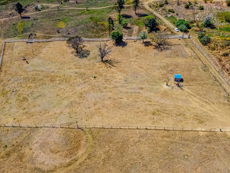 Aerial view of a large, open residential vacant land plot featuring perimeter fencing and a small shed structure.