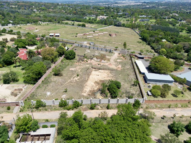 Aerial view of a vacant residential plot featuring perimeter walling and established boundary lines in a suburban setting.