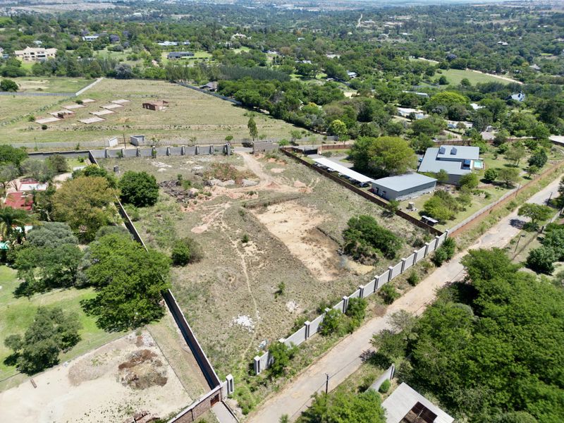 Aerial view of a vacant residential plot featuring perimeter walling and established boundary lines in a suburban setting.
